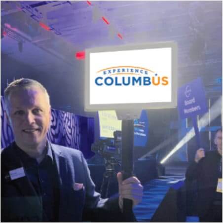 man holding a experience columbus sign