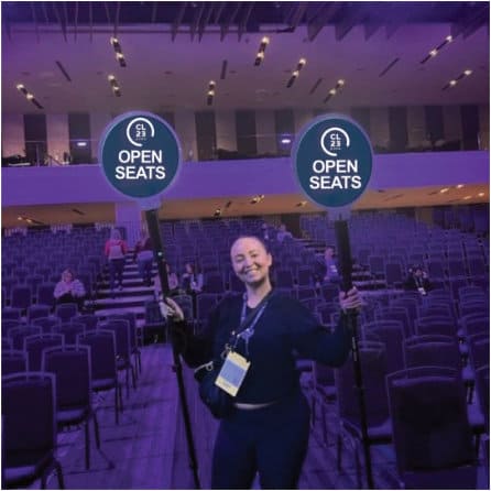 woman smiling while holding a open seats sign