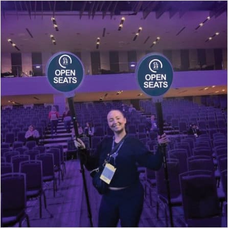 woman smiling while holding a open seats sign